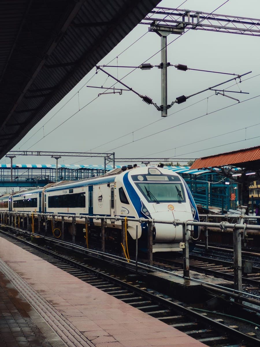 Vande Bharat Express train at a station platform under overhead electrification wiring